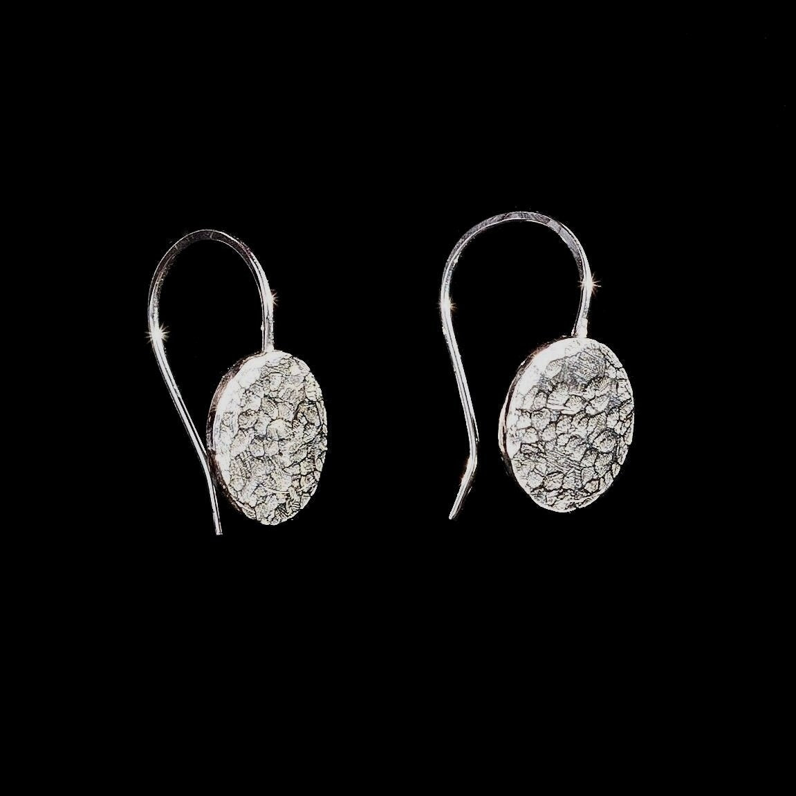 A pair of small silver circle discs with a hammered texture that are soldered onto silver ear wire